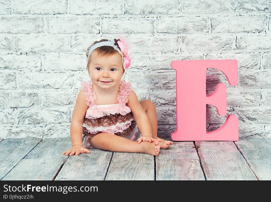 Beautiful and cute girl in pink dress with the letter E. Emotional girl.