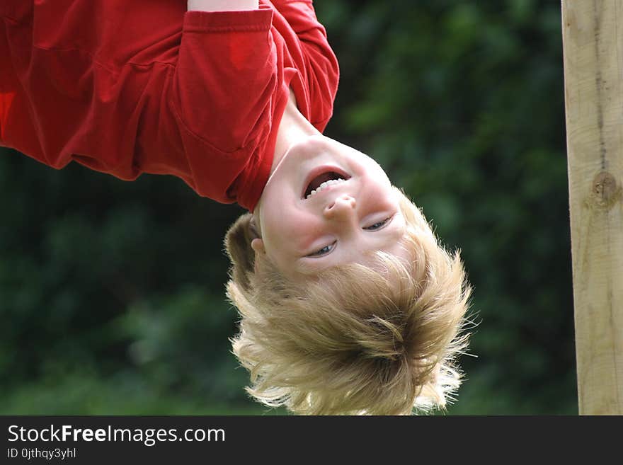 Happy Laughing Boy hanging upside down in a playground