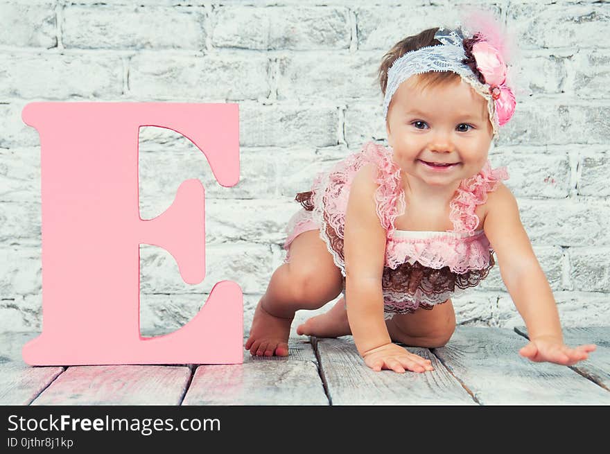 Beautiful and cute girl in pink dress with the letter E. Emotional girl.