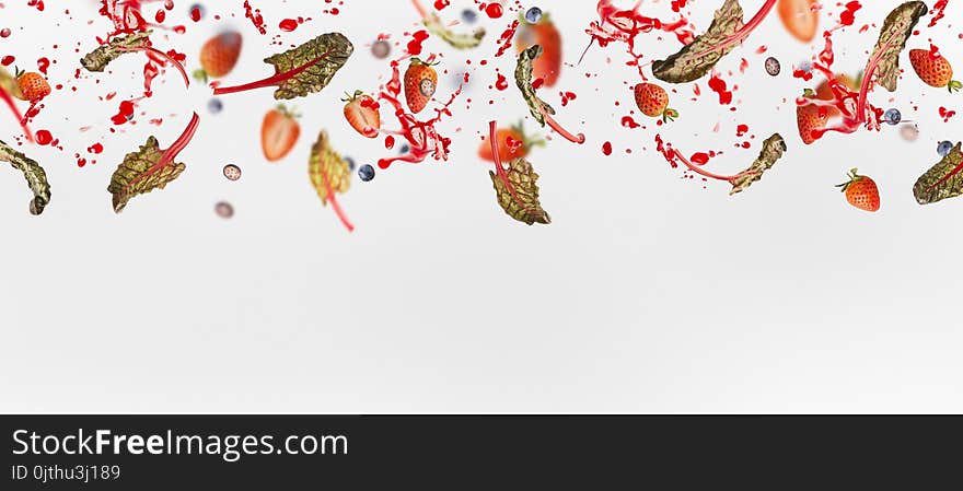 Various flying or falling berries with red chard leaves and splash of juice on white background, banner