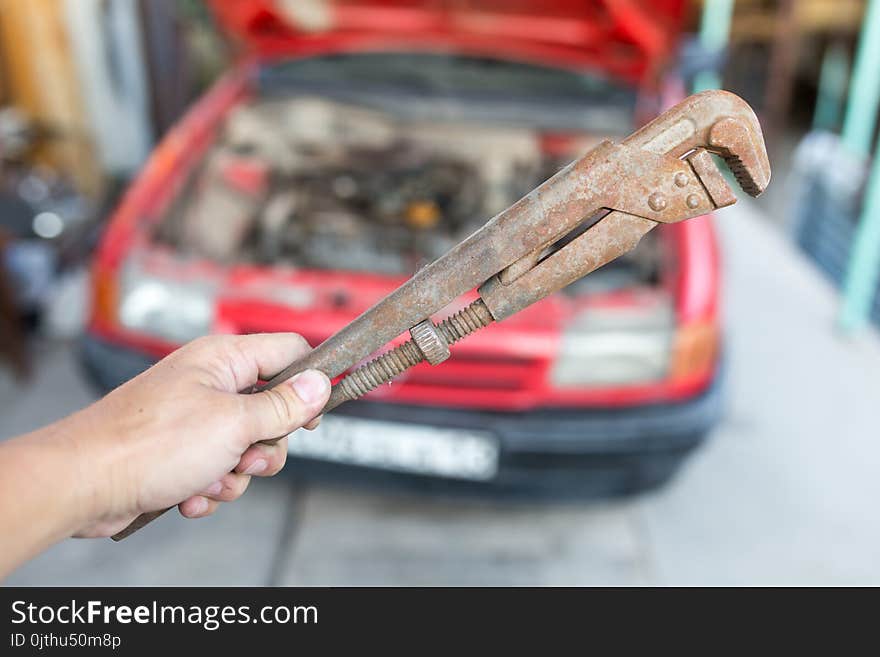 Wrench in hand on the background of cars .