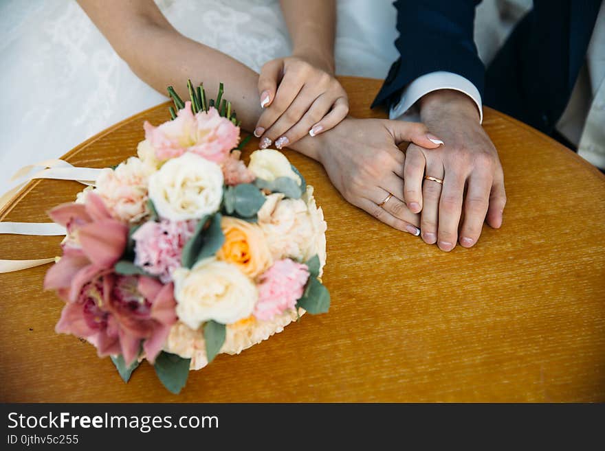 Closeup groom and bride are holding hands at wedding day and show rings. Concept of love family