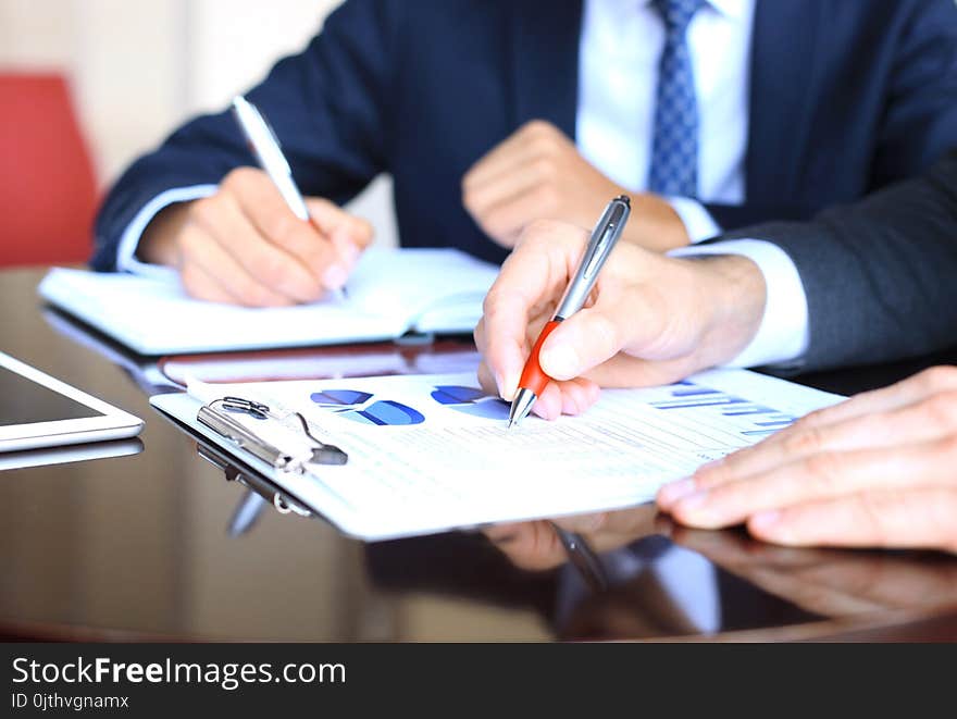 Two Young Businessmen Analyzing Financial Document At Meeting.