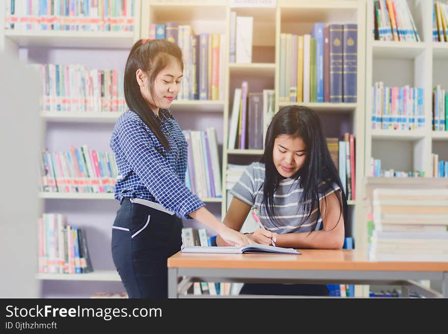 Portrait of clever Asian students doing research together in college library