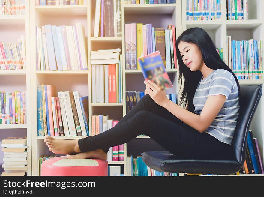 Portrait of clever Asian student reading and doing research in college library