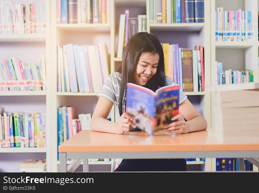 Portrait of clever Asian student reading and doing research in college library