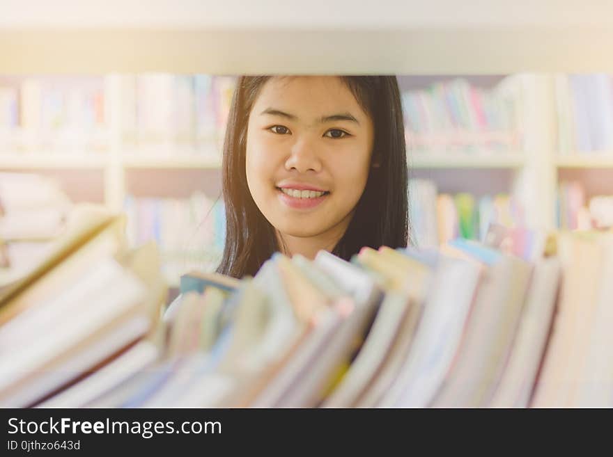 Portrait of clever Asian student reading and doing research in college library