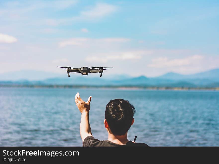 Man releasing flying drone quad copter with high resolution digital camera flying the sky with lake view