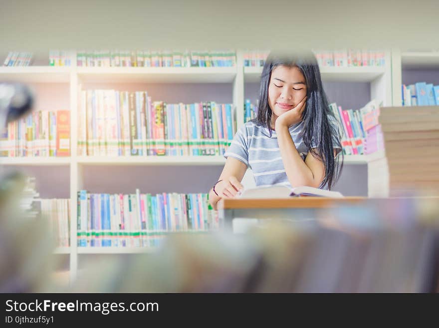 Portrait of clever Asian student reading and doing research in college library