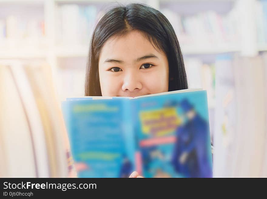 Portrait of clever Asian student reading and doing research in college library