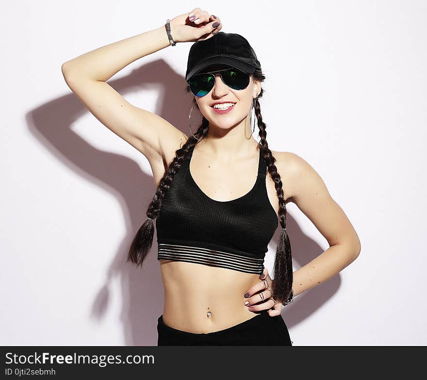 Portrait of a young woman in a cap and sunglasses over white bac