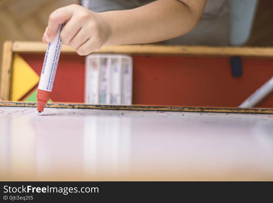 Child holding a pencil in whiteboard closeup