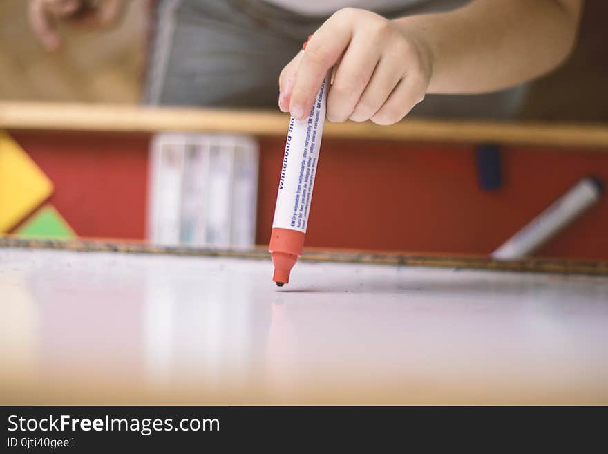 Child holding a pencil in whiteboard closeup