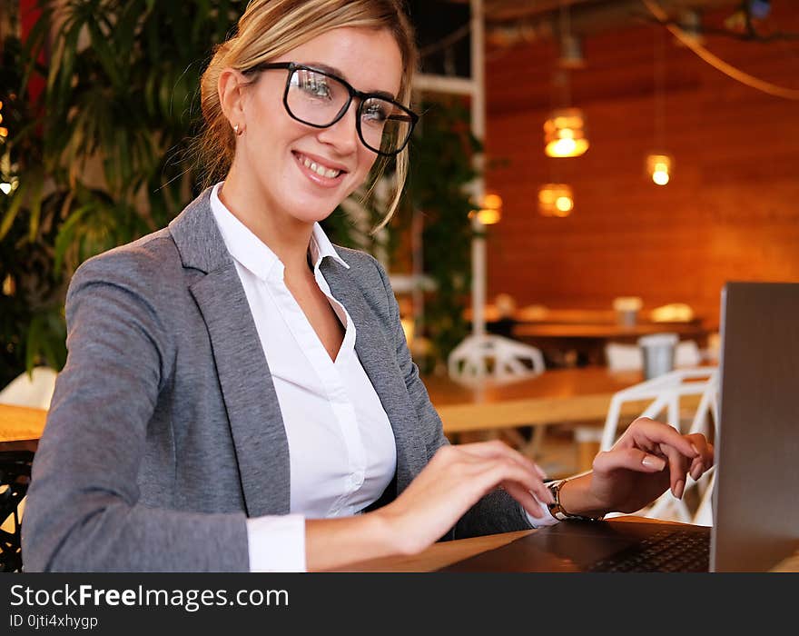 Business wooman using laptop at cafe. Young beautiful girl sitting in a coffee shop and working on computer. Lifestyle and business concept.