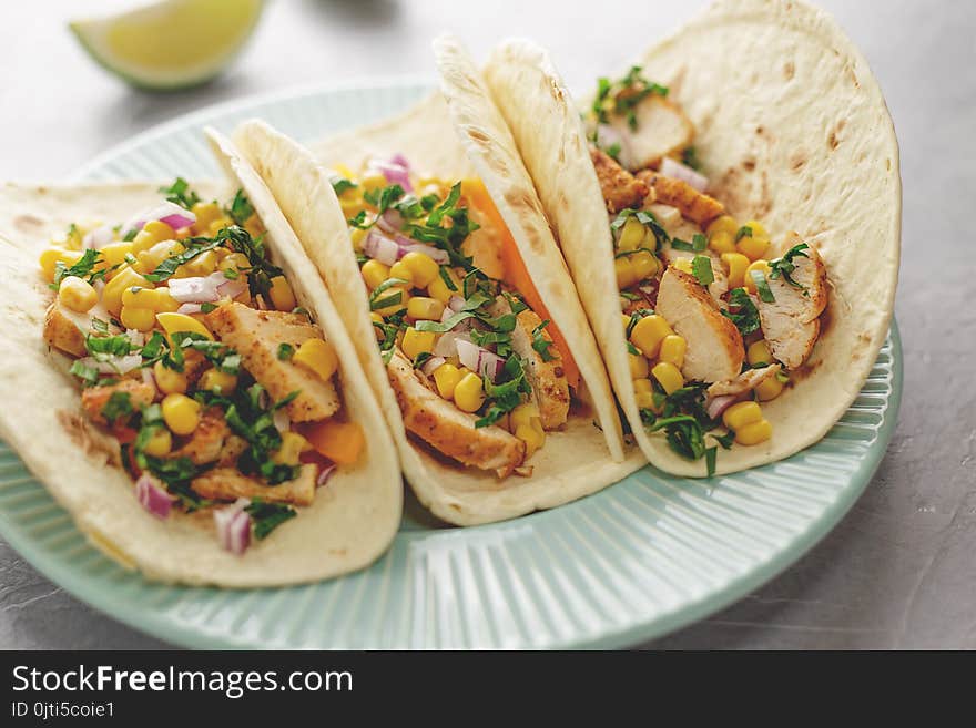 Blue plate with mexican food flatbread with chicken meat and vegetables on the table. Latin American snack tacos for lunch.