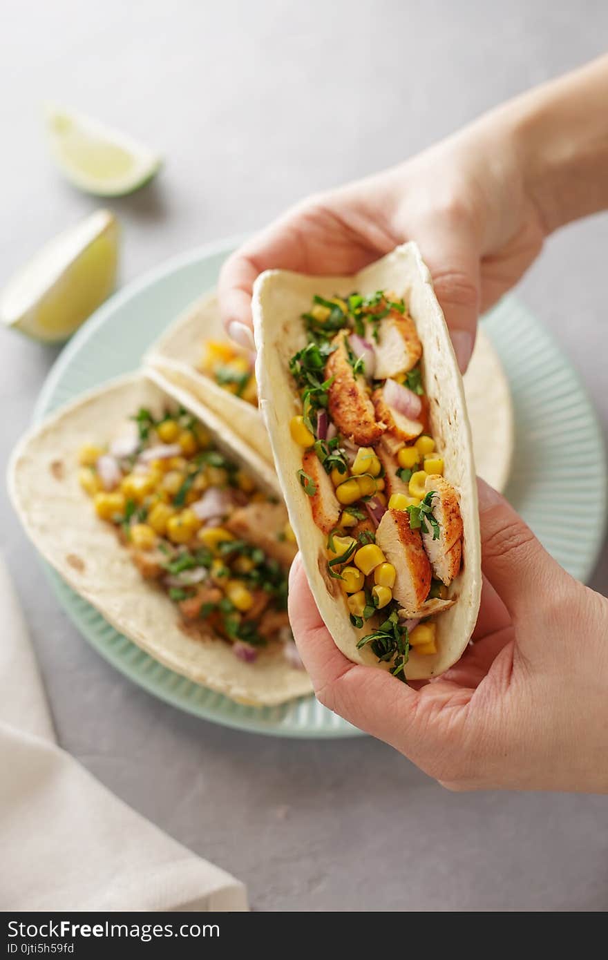 Hands Holding Tacos With Roasted Chicken Meat, Corn, Parsley, Salsa And Sweet Pepper.