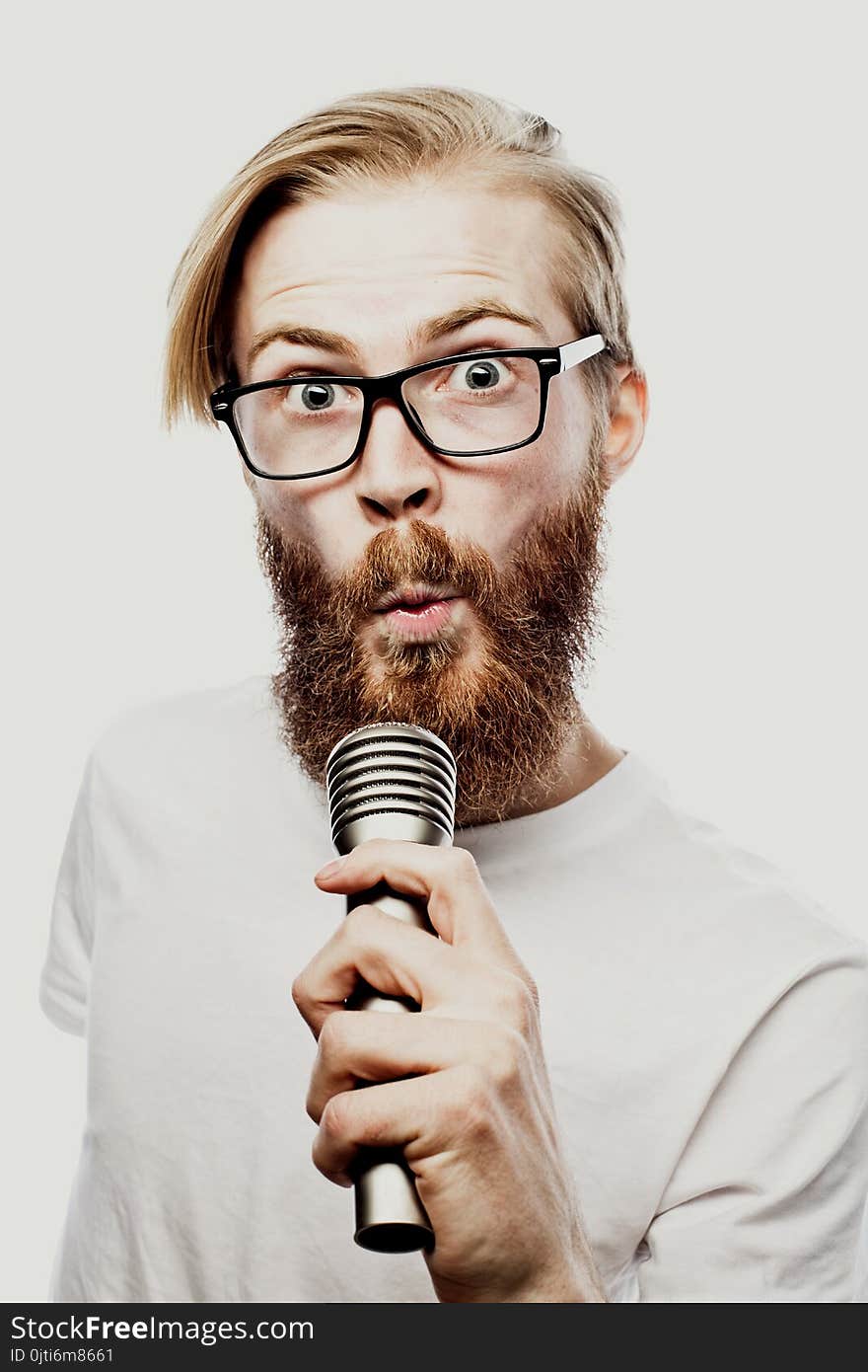 Lifestyle and people concept: young man singing with microphone, on white background