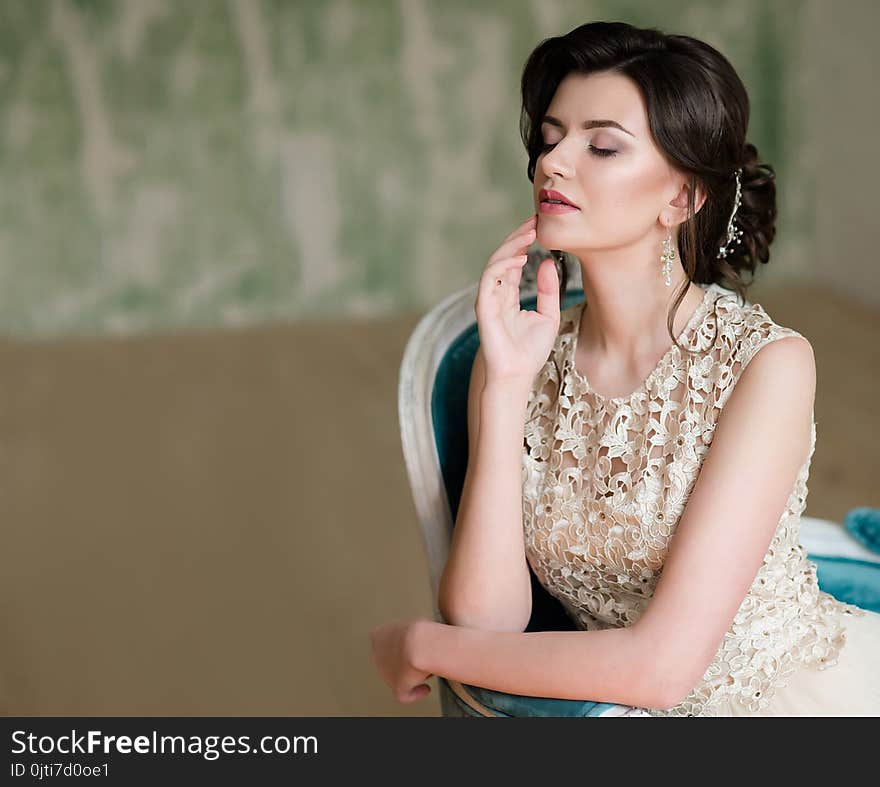 Half length portrait of brunette smiling woman dressed in sleeveless light evening dress