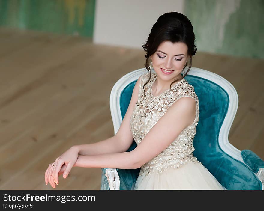 Half length portrait of brunette smiling woman dressed in sleeveless light evening dress.