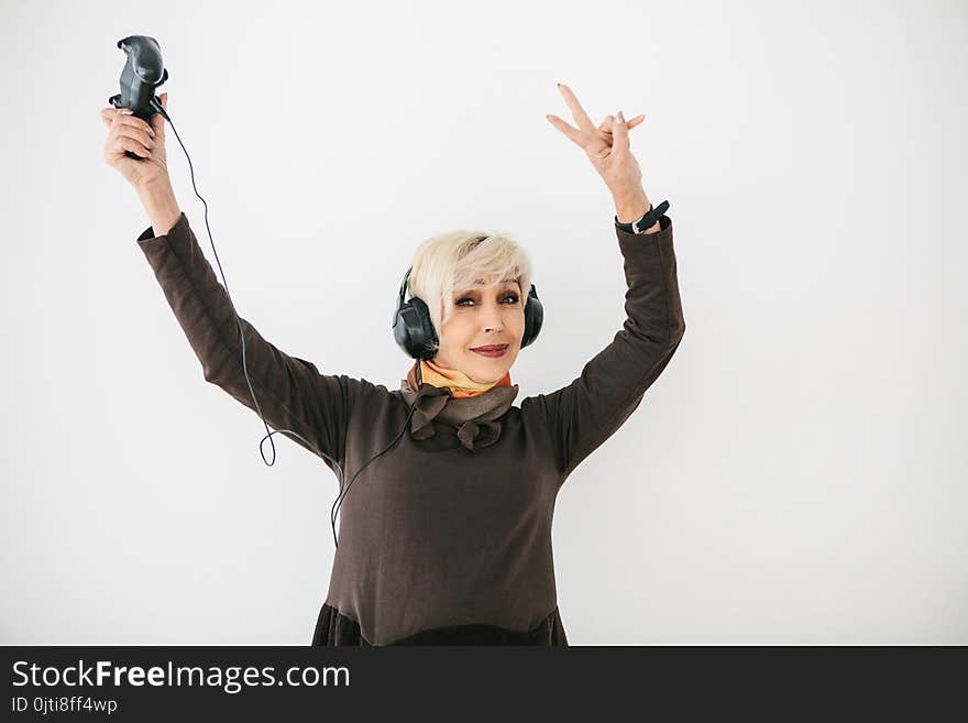 An elderly woman plays a video game and gestures that she won. Elderly person and modern technology.