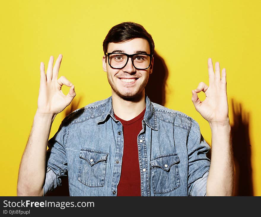 Portrait of a cheerful young man showing okay, studio shoot