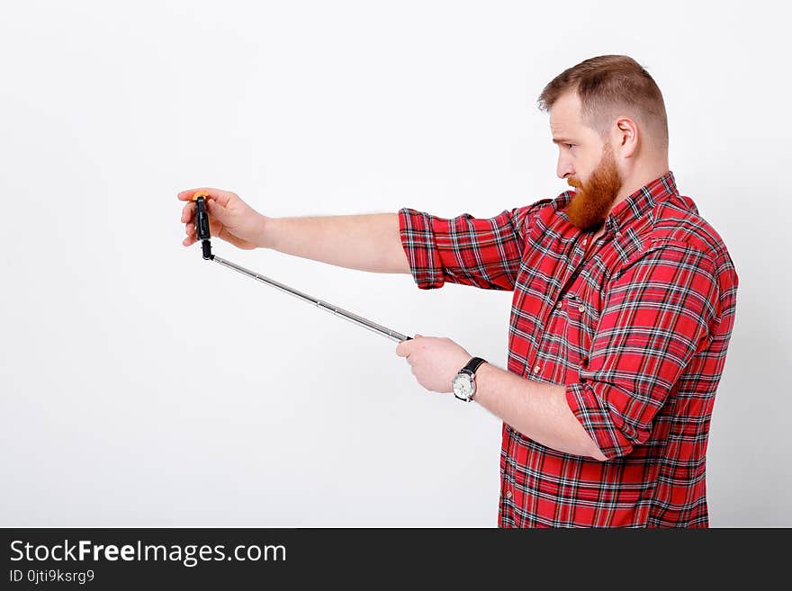 Man with red beard in plaid shirt makes selfie on phone. Man with red beard in plaid shirt makes selfie on phone