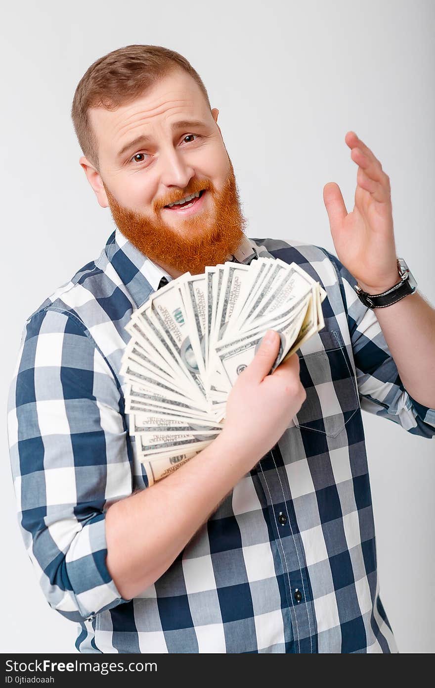 Young handsome smiling man with beard in plaid shirt holding a lot of hundred-dollar bills. money. Young handsome smiling man with beard in plaid shirt holding a lot of hundred-dollar bills. money