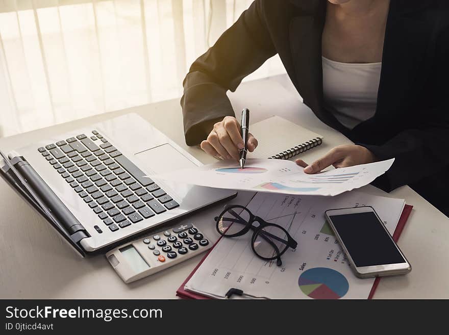 Businesswoman analyzing financial report with laptop in office