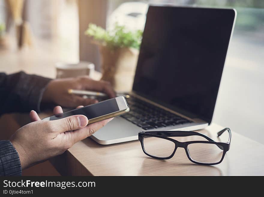 Businessman using laptop and smart phone in coffee shop