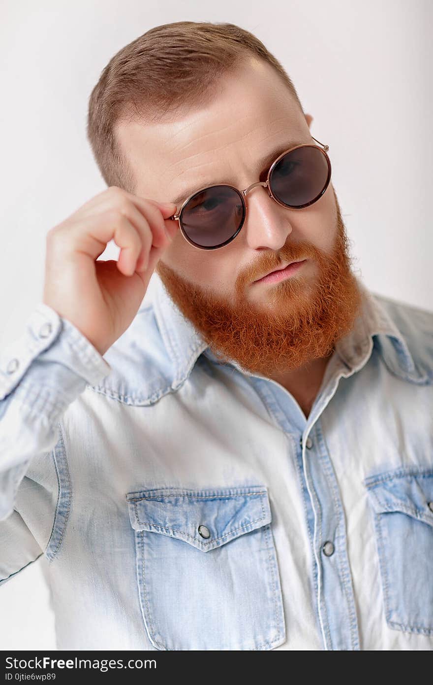 Close-up portrait of red-haired beard man in sunglasses and denim shirt