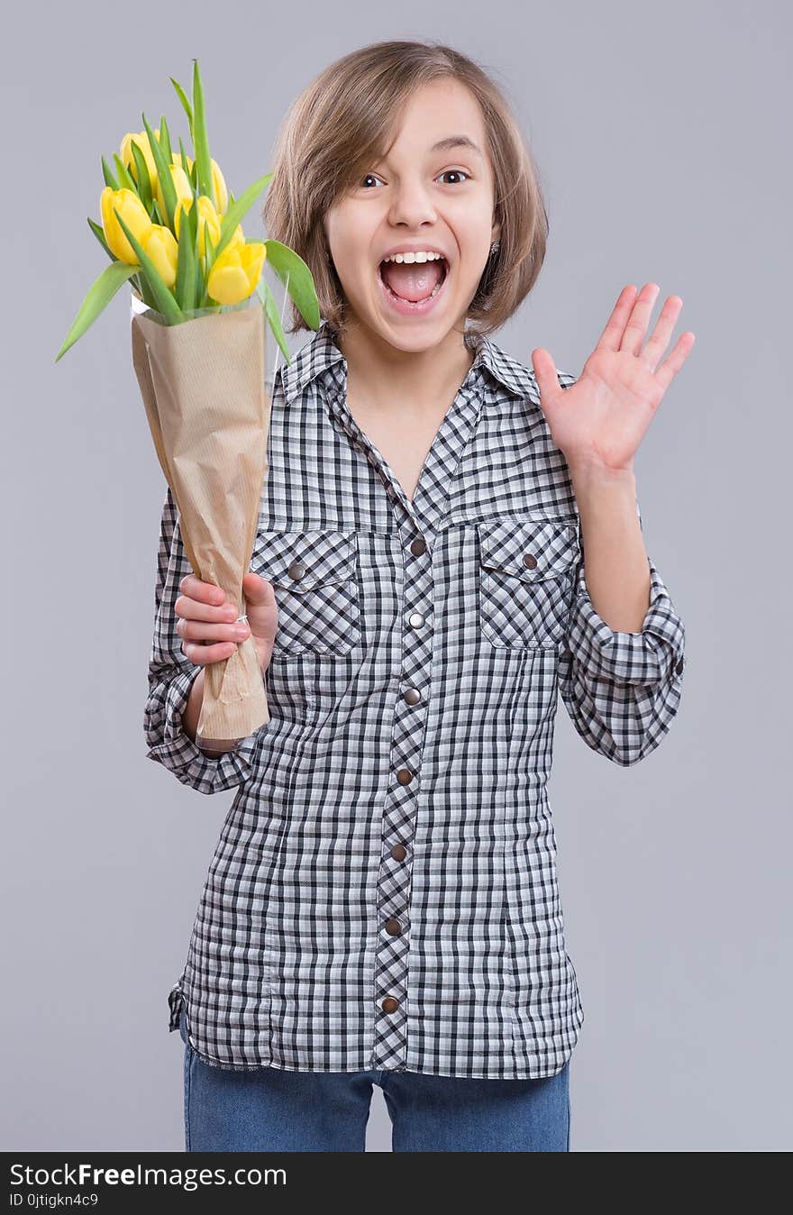 Beautiful girl with bunch of flowers on gray background. Smiling child with bouquet of yellow tulips as a gift. Happy mothers, Birthday or Valentines day. Beautiful girl with bunch of flowers on gray background. Smiling child with bouquet of yellow tulips as a gift. Happy mothers, Birthday or Valentines day.