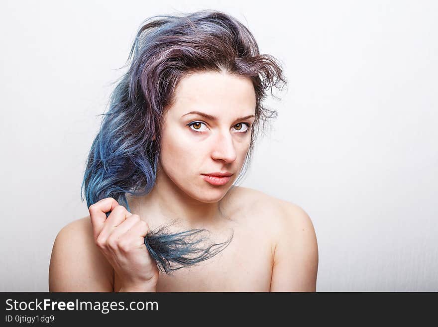 Young Woman Holding Her Colorful Damaged Hair In Her Hand