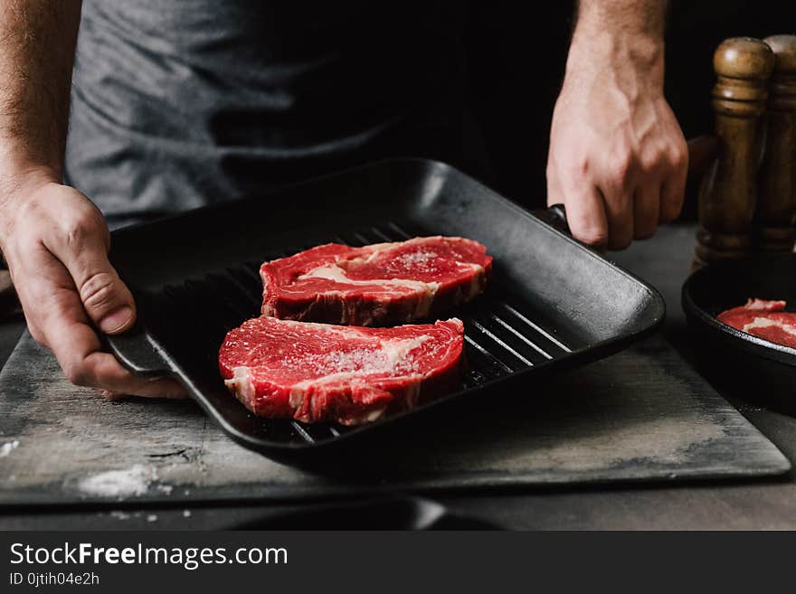 Male hands holding grill pan beef steaks Man cooking