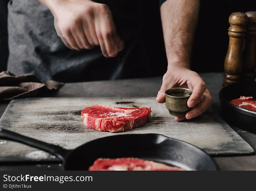 Male hands sprinkle salt beef steaks on the home kitchen