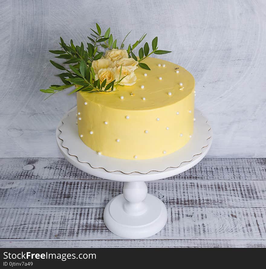 Yellow cream cheese cake with roses and greenery