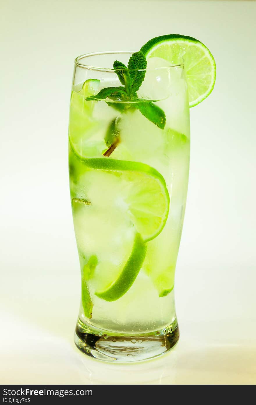 Summer cold drink mojito lime and mint with ice and soda with drops on a glass on a white background