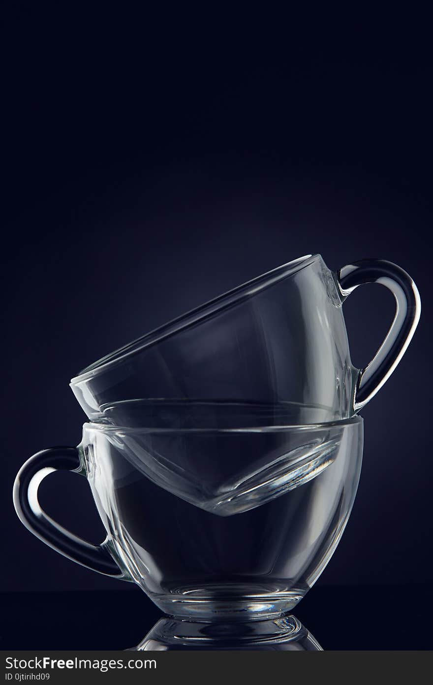 Conceptual Composition Of Two Glass Teacups Over Dark Grey Background, Close-up, Vertical.