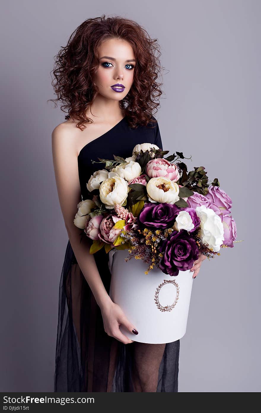 Beautiful Girl With Plump Lips In Black Body With A Bouquet Of Flowers In The Studio, Evening Hairstyle And Makeup