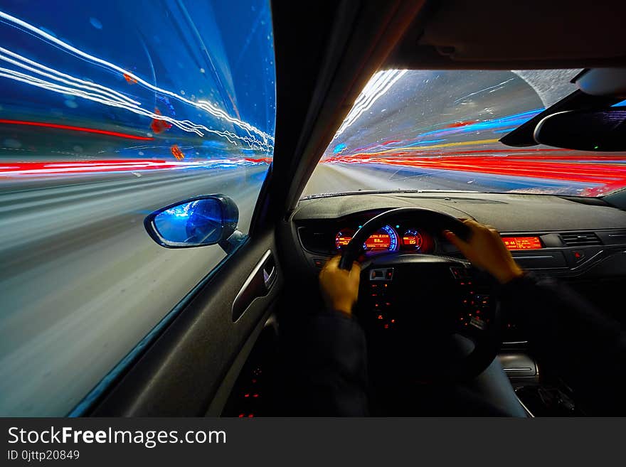 Movement of the car at night at high speed view from the interior with driver hands on wheel. Concept spped of life. Movement of the car at night at high speed view from the interior with driver hands on wheel. Concept spped of life.