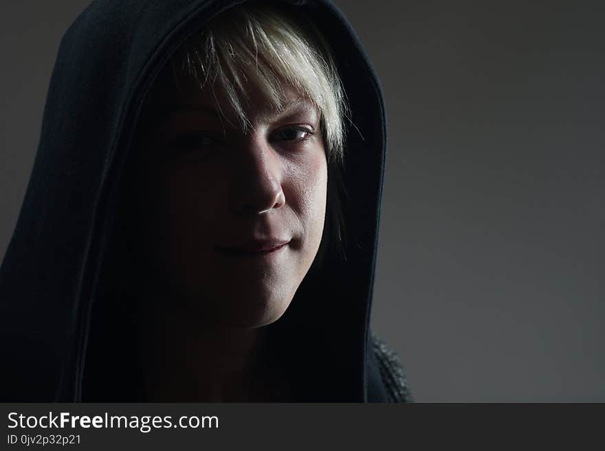 Young blonde girl portrait with a black hoodie, expression full of awareness