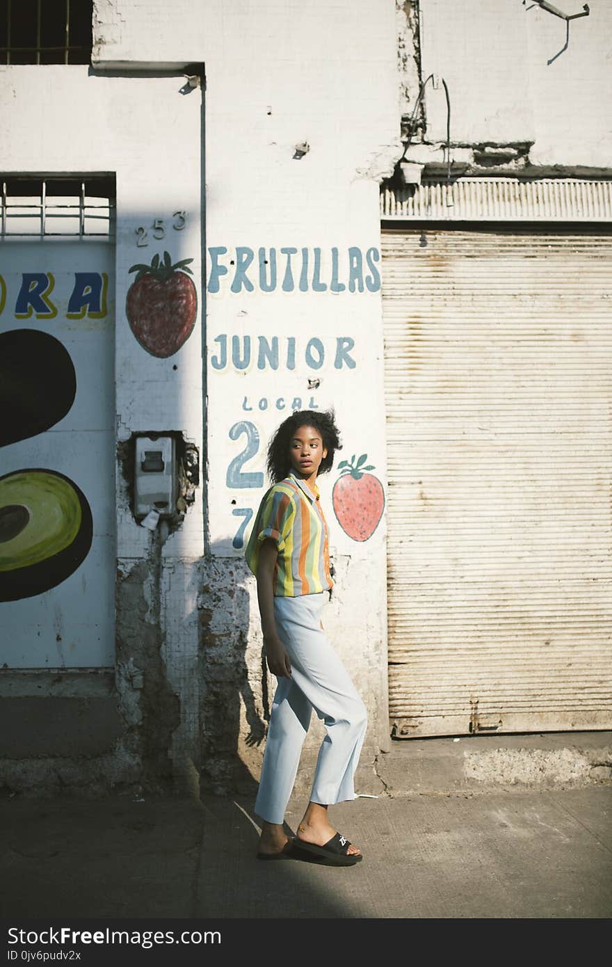 Woman in Yellow Mid-sleeved Shirt Standing Beside White Wall