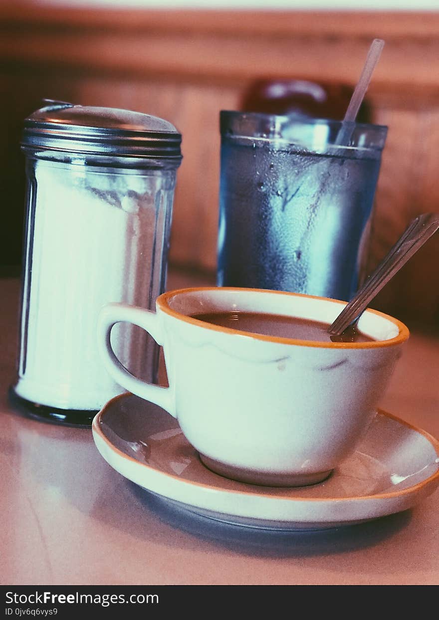 White Ceramic Mug Fill With Coffee Beside Condiment Shaker