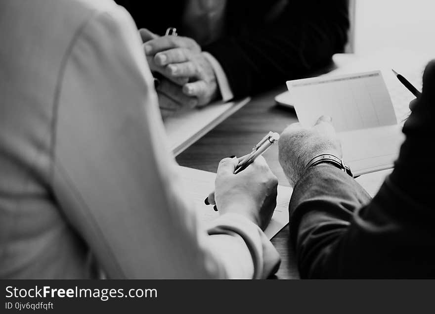 Grayscale Photo of Three Person Sitting Near Table