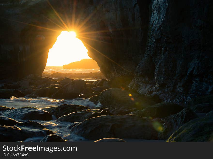 Cave Near Body of Water at Sunset