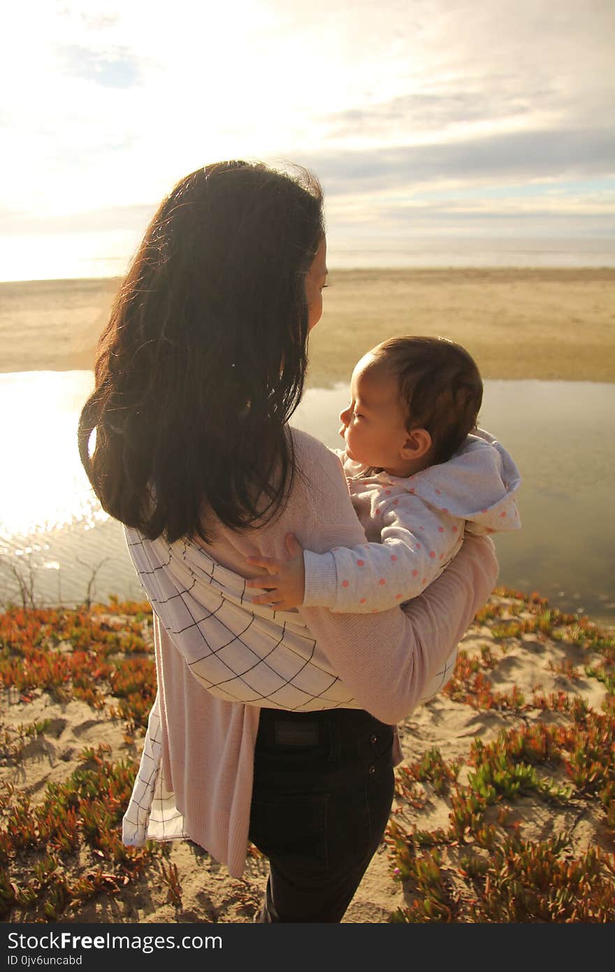 Mother and child spending quality time together on the beach. Baby sunbathing in the beach sunset. Mother and child have a close bond. Mother and child spending quality time together on the beach. Baby sunbathing in the beach sunset. Mother and child have a close bond.