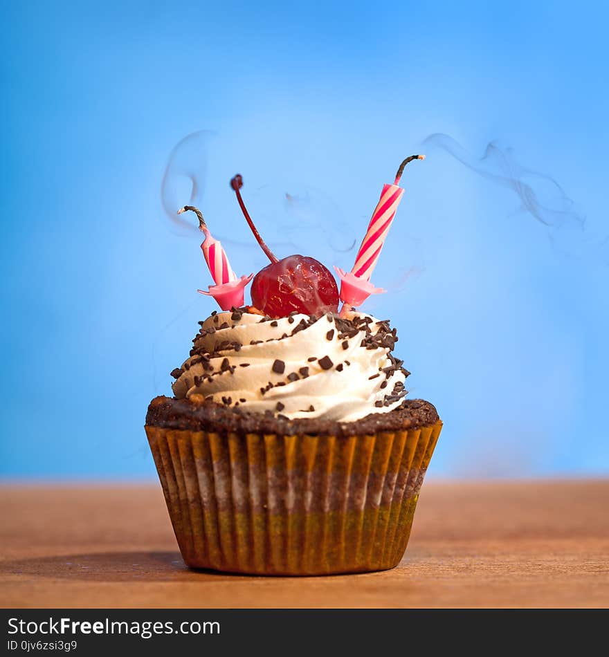 Birthday cupcake with blown out candles over bluye background