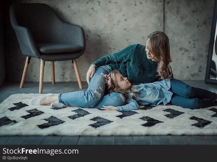 Smiling mother with her daughter in the room on the carpet