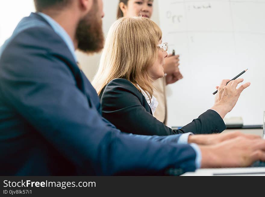 The view of a middle-aged business women presenting her vision and opinion about a project during a decision-making meeting in the conference room. The view of a middle-aged business women presenting her vision and opinion about a project during a decision-making meeting in the conference room