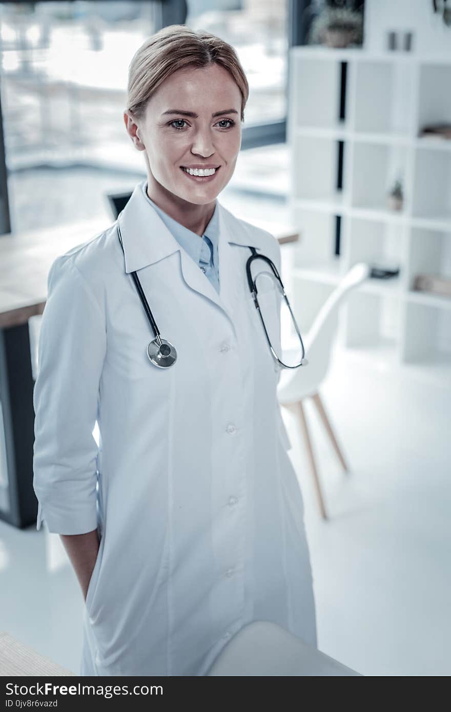 Ready for new task. Skilled pretty confident nurse looking straight and smiling being in the cabinet. Ready for new task. Skilled pretty confident nurse looking straight and smiling being in the cabinet.