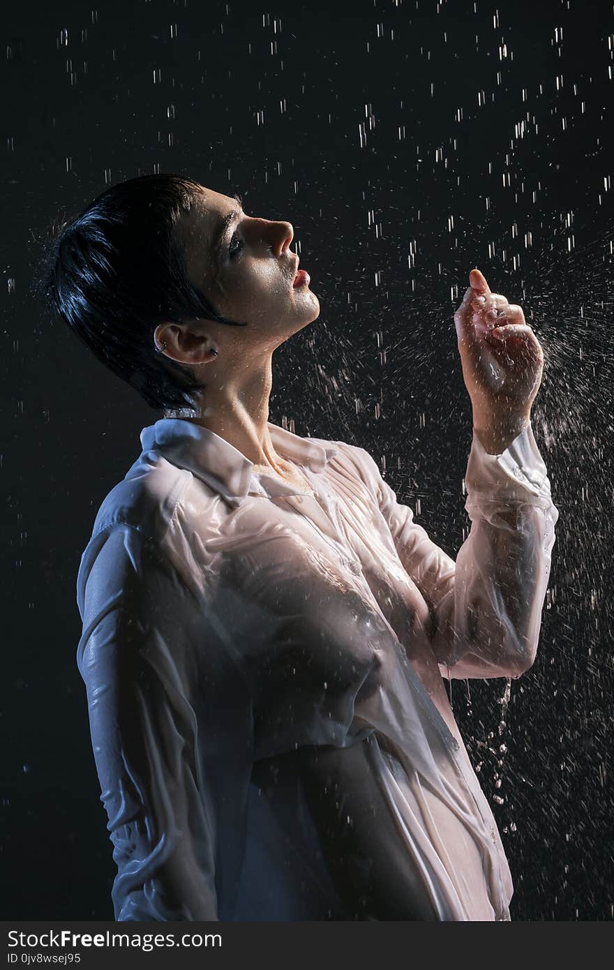 Brunette in wet shirt under water in the dark